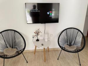 two chairs and a table with a tv on a wall at Camposol Villa Mazarron, Spain in Mazarrón