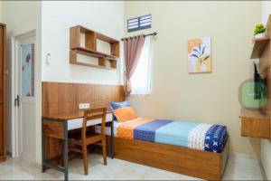 a bedroom with a desk and a bed and a table at Kost Putri Exclusive Orchidee in Jatingaleh