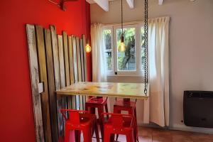a dining room with red walls and a wooden table and red stools at Mi Casa Tu Casa E , Céntrica y Pet friendly in Lago Puelo
