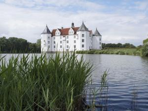 a large white castle sitting on top of a lake at West barn at Mühlendamm in Steinbergkirche