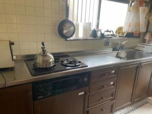 a kitchen with a stove with a tea kettle on it at 民泊　二見のおうち in Hutami