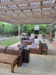 a patio with couches and tables under a wooden pergola at Nature's Retreat- A Bird Watchers Dream Location in San Benito