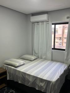 Un dormitorio pequeño con una cama con ventana. en Ed Louise Apts de 2 quartos, en Chapecó