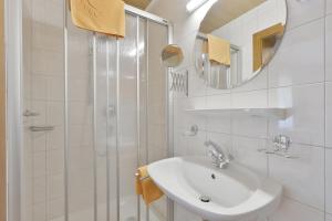 ein weißes Bad mit einem Waschbecken und einer Dusche in der Unterkunft Gästehaus Ahornblick in Mayrhofen