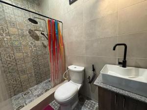 a bathroom with a toilet and a shower and a sink at Bisola Residences in Cotonou
