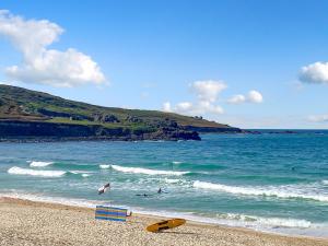 een strand met mensen in het water en een geel surfplank bij Ocean Breezes in St Ives +2 foto's