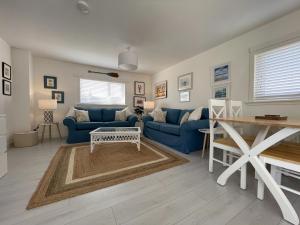 un salon avec des canapés bleus et une table dans l'établissement Well Cottages, à Portmahomack