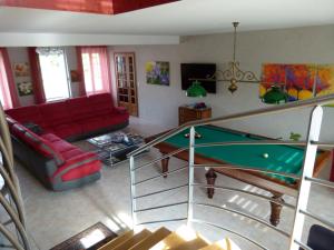 a living room with a red couch and a pool table at Gîte LAU'LIVIER- Piscine chauffée et couverte in Givarlais