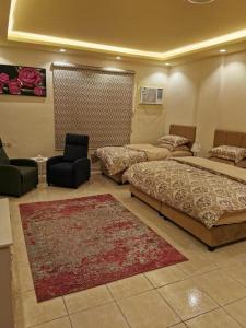 Habitación con 3 camas, silla y alfombra. en شقق المحبة, en Taif