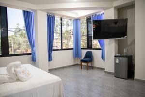 a bedroom with blue curtains and a bed and a tv at Cielo del Oriente Hotel in Pucallpa