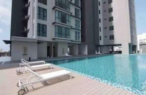 a swimming pool with two lounge chairs and two buildings at Deluxe Seaview Suite Tripe Bed with bath tub 13A in Tanjong Tokong