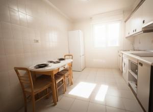 a kitchen with a table and chairs and a refrigerator at COSTA VASCA LEIOA - HoME in Leioa