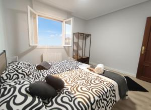 a bedroom with a black and white bed with a window at COSTA VASCA LEIOA - HoME in Leioa