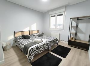 a bedroom with a bed with a black and white comforter at COSTA VASCA LEIOA - HoME in Leioa