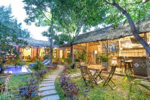 a house with a table and chairs in the yard at An Bang beach Happy Village in Hoi An