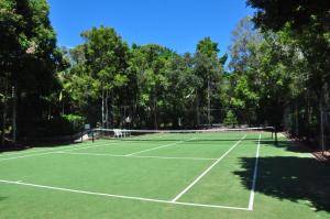 a tennis court with a net and some trees at Baden 26 - Rainbow Shores - Swimming pools - Tennis court - Walk to beach in Rainbow Beach