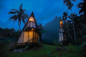 a small house with a lit up facade with palm trees at Sparrow's House in Weligama