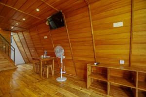 a room with a wooden wall with a fan and a table at Sparrow's House in Weligama