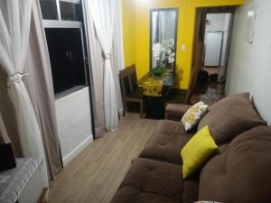 a living room with a brown couch and a yellow pillow at Frente ao Mar Residence in São Vicente +46 photos