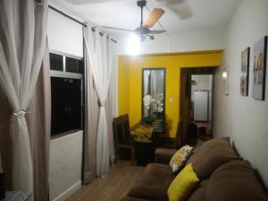 a living room with a couch and a yellow wall at Frente ao Mar Residence in São Vicente
