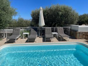 a swimming pool with chairs and an umbrella and a table at Nefeli Villas in Hersonissos