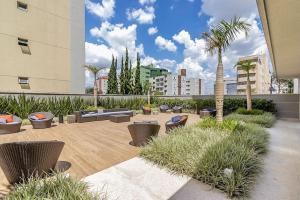 un cortile con divani, sedie e palme di Flat Região Nobre a Curitiba