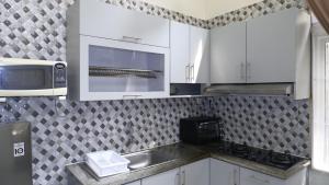a kitchen with white cabinets and a sink and a microwave at Diyar Villas Puncak R7-3 in Puncak
