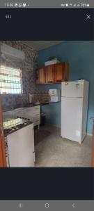 a kitchen with white appliances and a blue wall at Casa de Praia em Salinopolis-Pará in Salinópolis