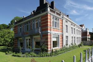 a large brick building in a yard with a fence at Group Villa with Pool & Sauna in Wanze