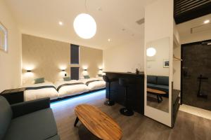 a hotel room with four beds and a desk at Hotel QOL 瓦町 in Takamatsu