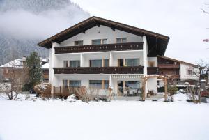 een groot gebouw in de sneeuw voor een berg bij Gästehaus Ahornblick in Mayrhofen