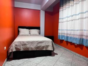 a bedroom with a bed with an orange wall at Qoyllur in Carhuaz +4 photos