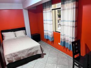 a bedroom with orange walls and a bed and a window at Qoyllur in Carhuaz