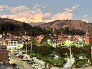 a city with cars parked on a street with mountains at Qoyllur in Carhuaz