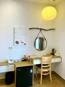 a desk with a mirror and a table with a chair at Triland Hotel in Phú Quốc