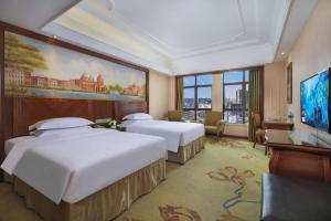 a hotel room with two beds and a television at Vienna International Hotel Nanning Railway Station Mingxiu Road Metro Station in Nanning