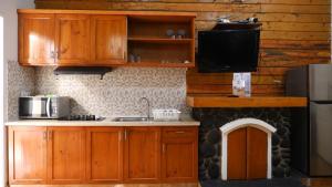a kitchen with wooden cabinets and a sink and a microwave at Diyar Villas Puncak Q4/11 in Puncak