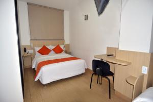 a bedroom with a bed and a desk with a chair at Hotel Granada Plaza in Manizales