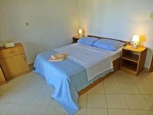 a bedroom with a bed with blue sheets and two lamps at Apartments Radic in Rogoznica