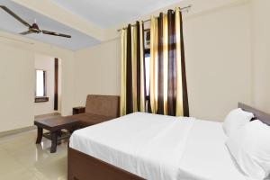 a bedroom with a white bed and a chair at Hotel O Ashoka in Kota