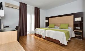 a bedroom with a large bed with green pillows at Hotel Baviera in Marbella