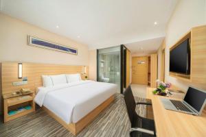 a bedroom with a bed and a desk with a laptop at City Comfort Inn Nanning Wuyi Fude in Nanning