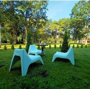 drei weiße Stühle und ein Tisch im Gras in der Unterkunft Aste loft maja in Aste