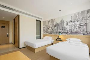 twee bedden in een kamer met een schilderij aan de muur bij City Comfort Inn Liuzhou Gubu Street Ma'anshan Park in Liuzhou +219 foto's