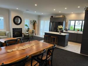 a living room with a wooden table and a kitchen at Pool, Spa pool, Private, Modern, Clive! in Clive