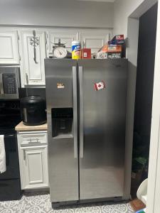 a stainless steel refrigerator in a kitchen with white cabinets at Gladelle in South Saint Paul