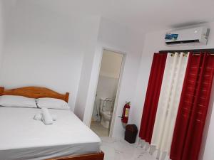 a bedroom with a bed and a red curtain at M and A Guesthouse in San Juan