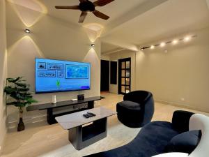 a living room with a flat screen tv and chairs at Balinese Corner Private Pool Near Sunway Pyramid Upto 24P in Subang Jaya