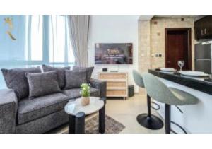 ein Wohnzimmer mit Couch und Tisch und eine Küche in der Unterkunft Al Reef Modern Escape -Sleek, Sunny & Serene in Abu Dhabi + 21 Fotos