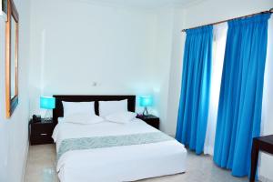 阿比让Hotel Djigui的卧室里有一张带蓝色窗帘的大床